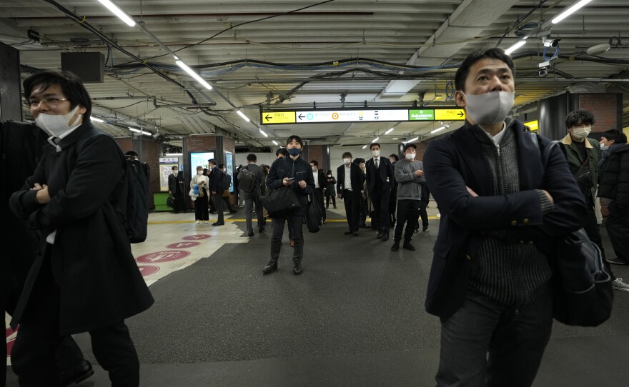 People wait at a train station in Tokyo on Wednesday, as all services were suspended after the 7.3 magnitude earthquake hit.