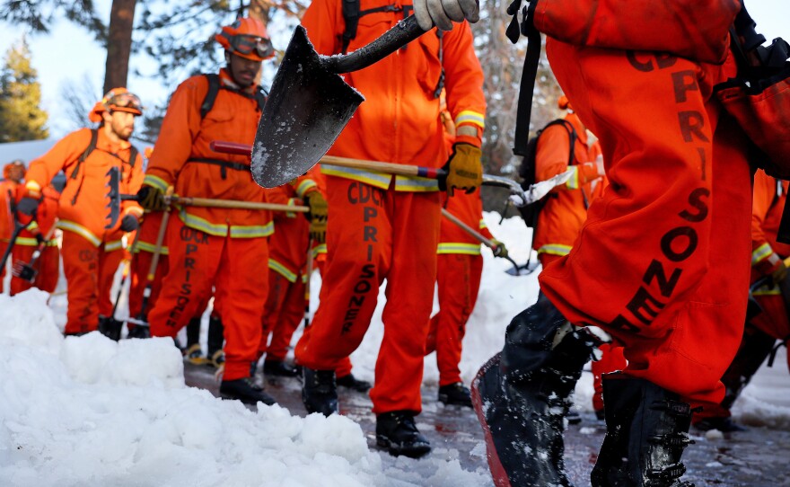 A crew of prisoner firefighters walk back to their vehicle on March 3 after shoveling and clearing snow after a series of winter storms in the San Bernardino Mountains in California.