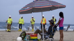 Workers in protective suits continue to clean the contaminated beach in Huntington Beach, Calif., on Oct. 11, 2021.