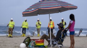 Workers in protective suits continue to clean the contaminated beach in Huntington Beach, Calif., on Oct. 11, 2021. 