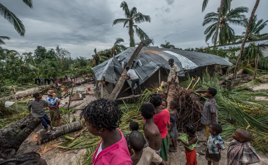 A man tries to cut up a tree that has crushed part of his house in Macomia.