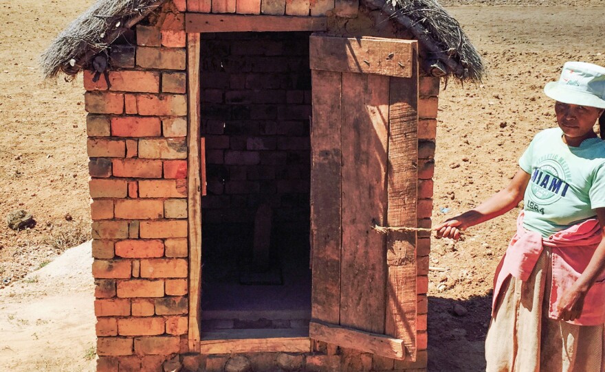 A woman in Madagascar stands by one of the new latrines in her village.