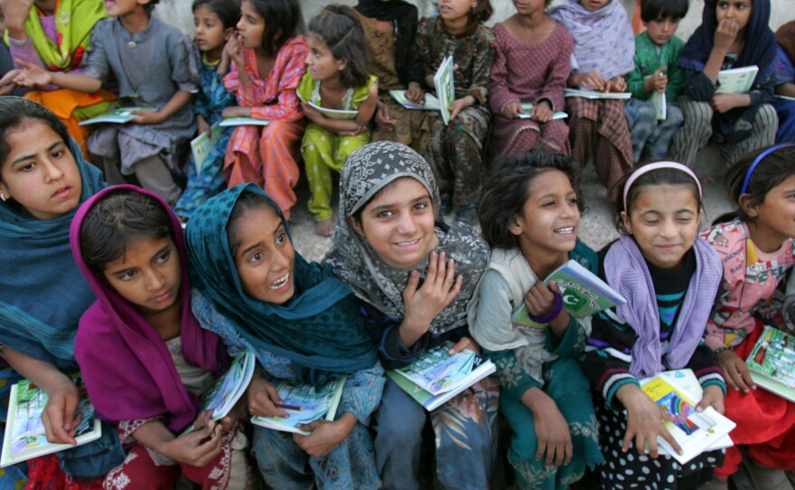 Young schoolgirls receive new notebooks and textbooks at a refugee camp in Muzaffarabad, Pakistan. Many girls in Pakistan still don't receive an education.