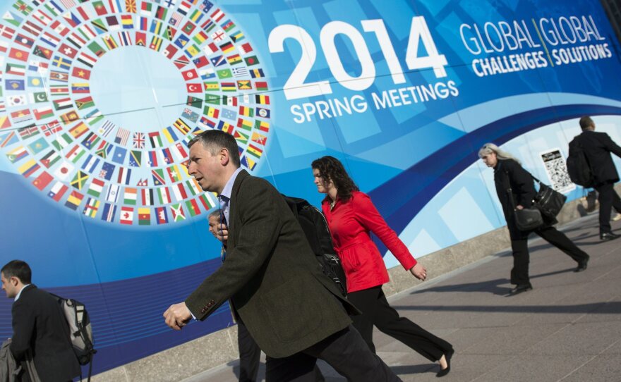 Pedestrians walk by the International Monetary Fund headquarters in Washington, D.C., site of the IMF/World Bank spring meetings.