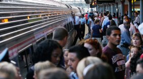 A crowd of New York-bound train passengers stands on the platform at the Trenton, N.J., train station as a full Amtrak train prepares to depart.