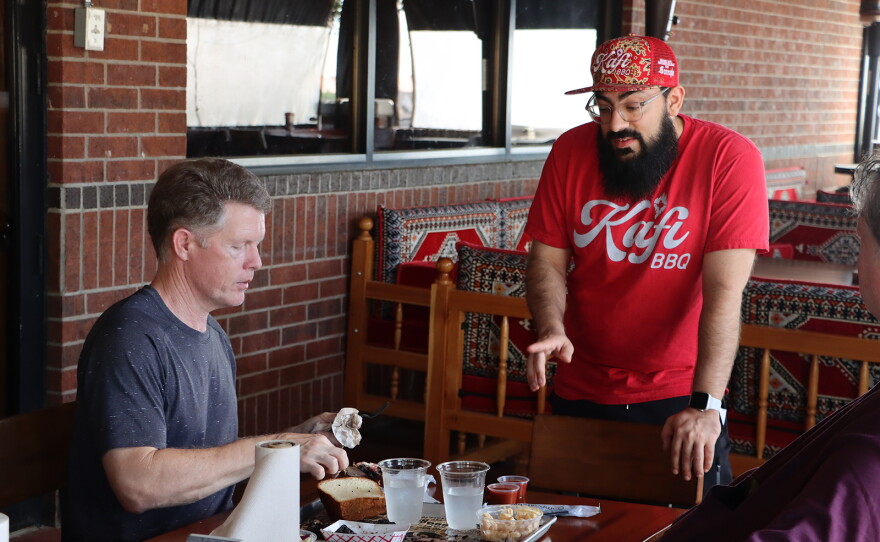 Kafi BBQ owner Salahodeen Abdul-Kafi (center) speaks with customer Jonathan Tate in Irving, Texas.