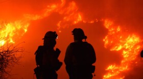 In this early morning Sunday, Dec. 10, 2017 photo released by Santa Barbara County Fire Department, firefighters working on structure protection, keep a close eye on nearby flames atop Shepard Mesa Road in Carpinteria, Calif. 