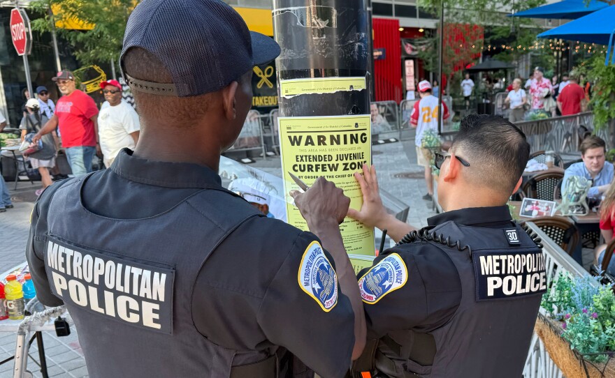 Washington D.C. Metropolitan Police officers place signage on a light pole informing the public that the area near the Nationals Park is under designate targeted juvenile curfew zone for youth under the age of 18.