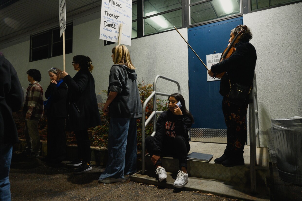 Diana Perez, 28, listens to the Sweetwater District Board meeting as she sits on the steps outside on Jan. 29, 2024. Chula Vista High School, where Diana's sister goes, is facing rumored schedule changes and the loss of specialized teachers.