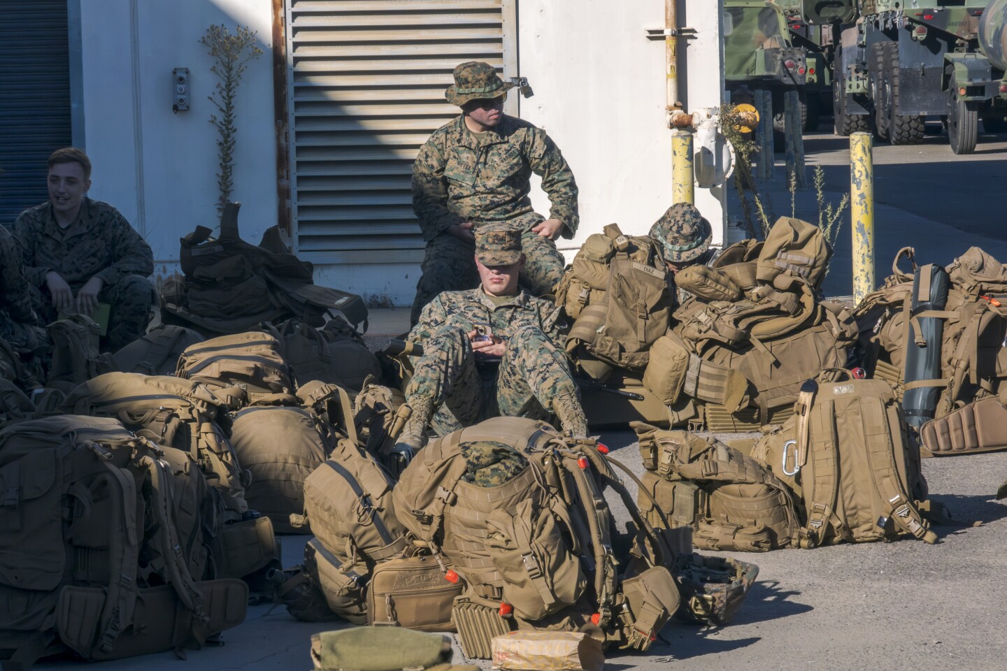 Marines wait with packed rucksacks on Marine Corps Air Station Miramar to load up into Humvees and 7-ton-trucks to head out on a training exercise east of the I-15 freeway, Oct. 22, 2024.