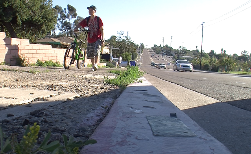 A cyclist walks his bike along an informal sidewalk on 54th Street, Feb. 12, 2016.