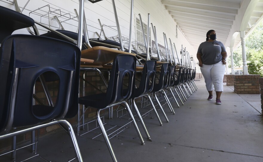 Kristina Washington, special education staff member at Desert Heights Preparatory Academy, walks past desks and chairs at the closed Glendale, Ariz., school in early June.