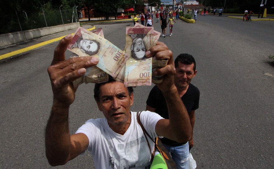 A man shows 100-Bolivar notes while crossing the Francisco de Paula Santander international bridge, linking Urena, in Venezuela and Cucuta, in Colombia Saturday, despite the border closing order issued by the Venezuelan government.