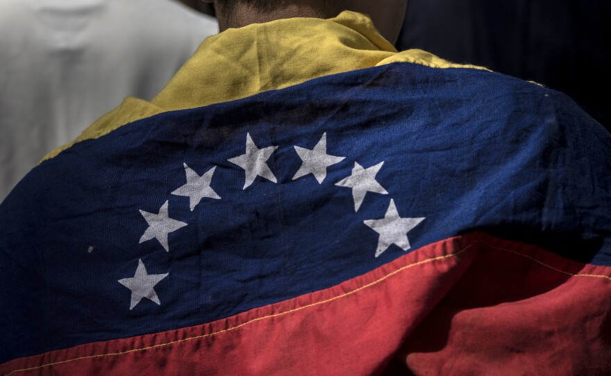 An attendee wears a Venezuelan flag during a rally in Caracas Friday with Juan Guaido, president of the National Assembly, who swore himself in as the leader of Venezuela.