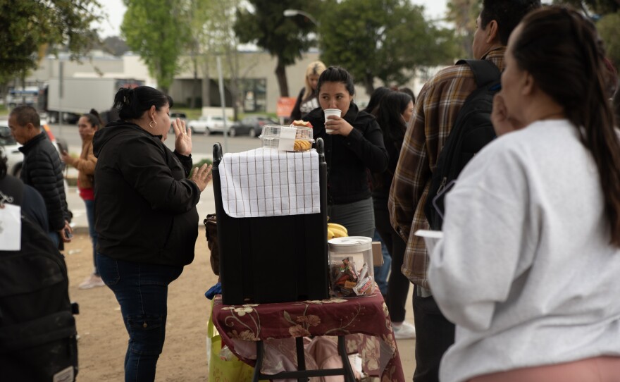 Local vendors sell coffee, donuts and fresh fruits at the Iris Avenue Transit Center in San Ysidro, April 19, 2024. Between 400 and 600 migrants are released into San Diego every day. 