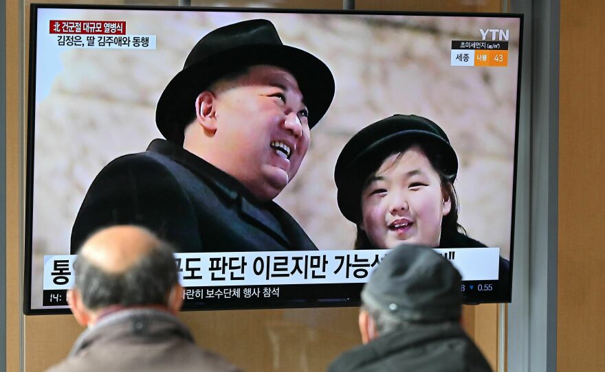 People watch a television screen showing a news broadcast with an image of Kim Jong Un and his daughter attending a military parade held in Pyongyang in February.