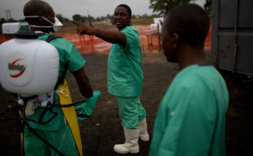 Protected by layers of gear, health care workers prepare to enter the isolation ward of the new Ebola treatment facility.