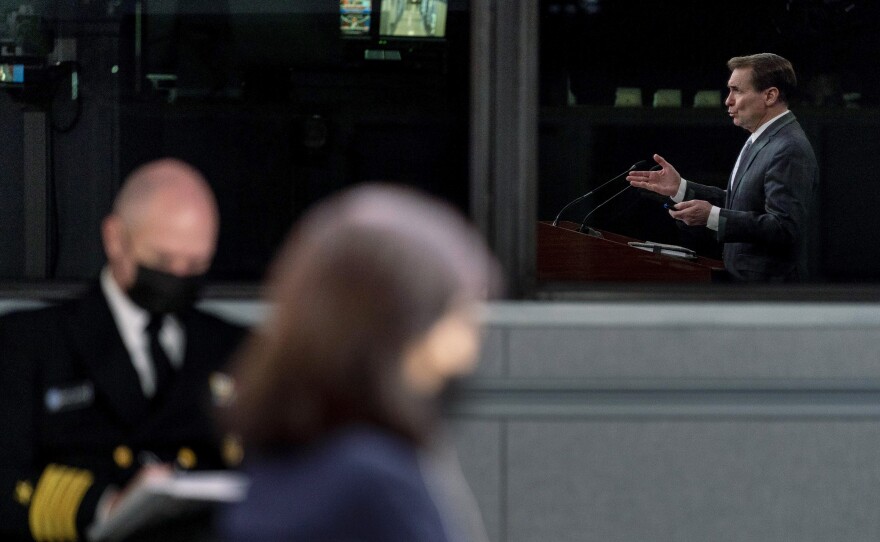Pentagon spokesman John Kirby, seen in reflection, speaks during a briefing at the Pentagon in Washington on Feb. 2. President Joe Biden is sending about 2,000 troops from Fort Bragg, N.C., to Poland and Germany this week and sending part of an infantry Stryker squadron of roughly 1,000 troops based in Germany to Romania.