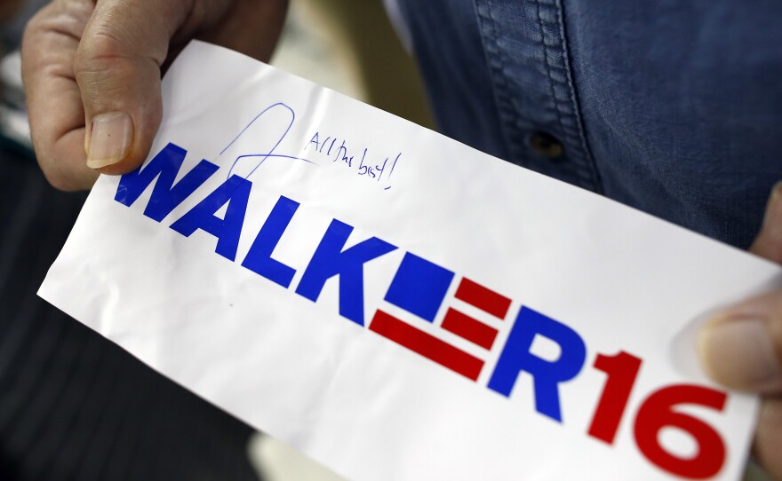 A supporter displays an autographed sticker for Walker at a town hall.
