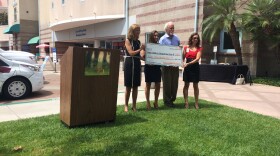 Ginny and Madison Scharbarth present a check to Charles Wilson of the Chadwick Center and Mindy Collins of Rady Children's Hospital on June 29, 2015.