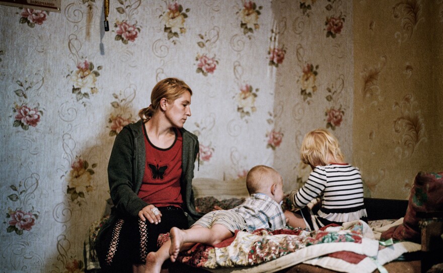 Olga Grinik and her children at their old home in Avdiivka, Donetsk region, which they recently learned has been destroyed. July 2019.