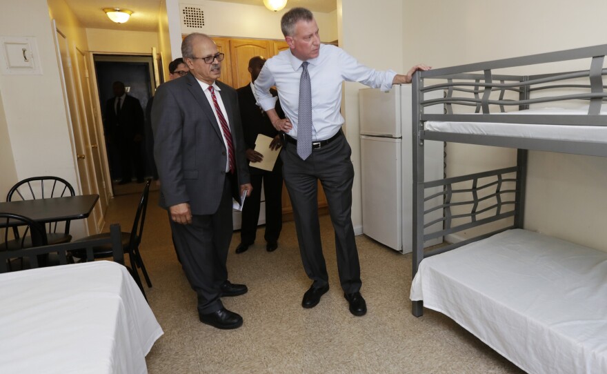 New York Mayor Bill de Blasio (right) visits a room at the Corona Family Residence, a homeless facility in the Queens borough of New York, in May.