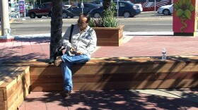 A resident sits on a bench at the corner of Euclid and Imperial avenues in San Diego, Oct. 31, 2015.