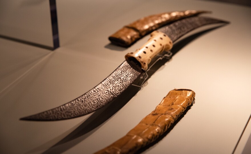 This double-bladed dagger, with the design on the blade etched with acid, is from late 19th-century Sudan and is made of iron, bone and crocodile skin.