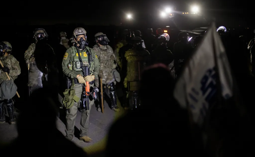A line of federal immigration agents and protesters stand-off near the Glass House Farms facility outside Camarillo on July 10, 2025. Protesters gathered after federal immigration agents conducted an immigration raid earlier in the day.