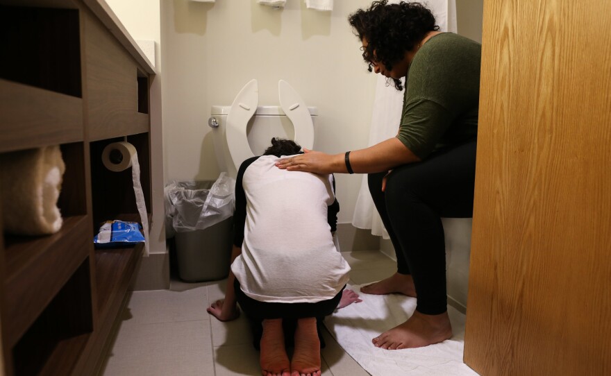 Melissa comforts Lola after she vomits from taking her chemo. Lola's physical symptoms were extreme; the medical trial she entered was all about how much she could withstand.