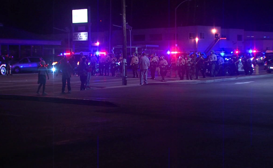Protesters and law enforcement officers stand on a street in El Cajon, Oct. 17, 2016.