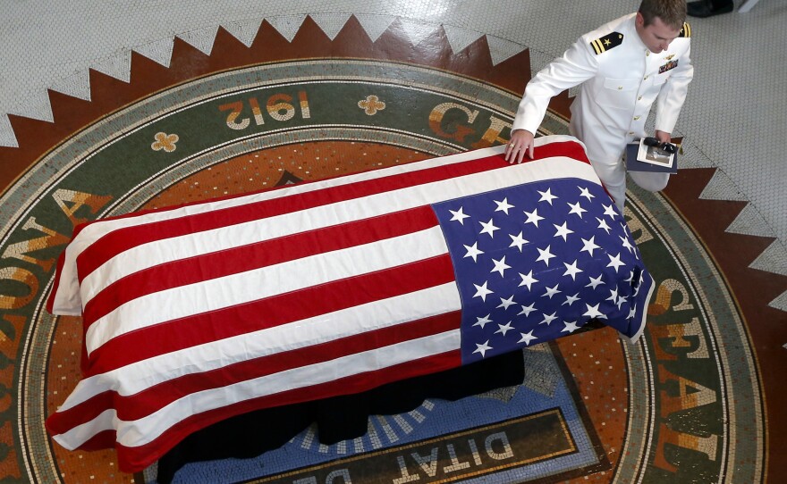 Jack McCain, son of Sen. John McCain, R-Ariz., touches his father's casket during a memorial service at the Arizona Capitol on Wednesday in Phoenix.