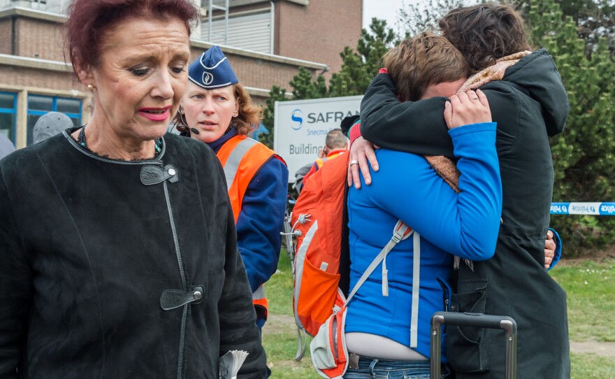 People stand outside the Brussels airport after the explosions. Belgium issued a Level 4 alert, denoting "serious and imminent attack."