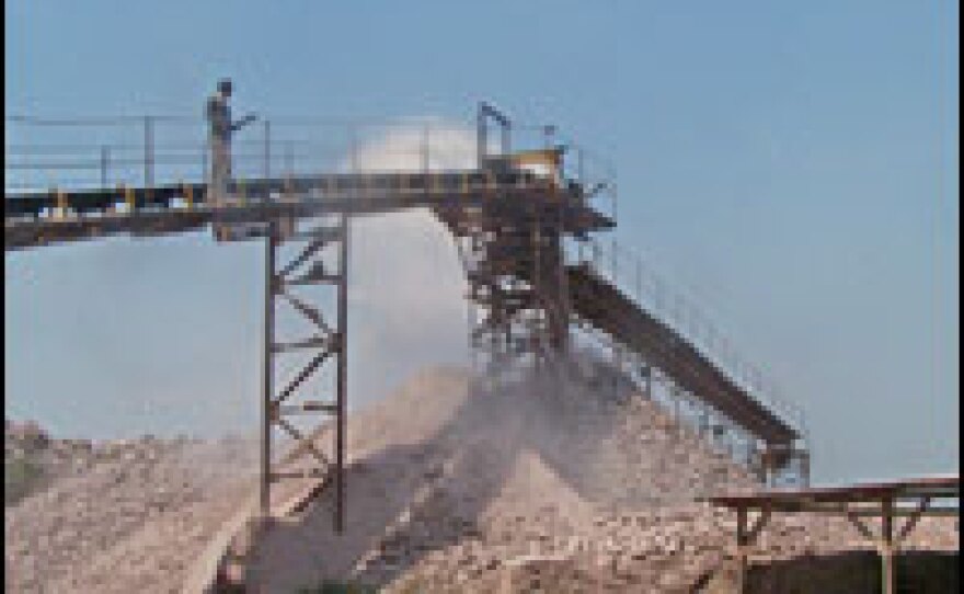 Heavy equipment in use at the quarry grinds big boulders into gravel, which is then carried by a conveyor belt and dumped in a pile to be trucked to the dam construction site.