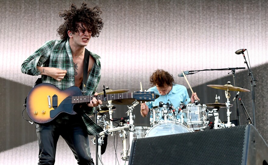 Healy (with guitar) and drummer George Daniel onstage during the 2016 Coachella Valley Music & Arts Festival.