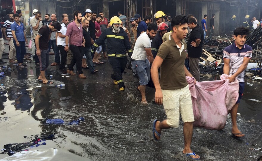 Iraqi firefighters and civilians evacuate bodies of victims killed from a bomb at a commercial area on Sunday in Karada neighborhood, Baghdad, Iraq.
