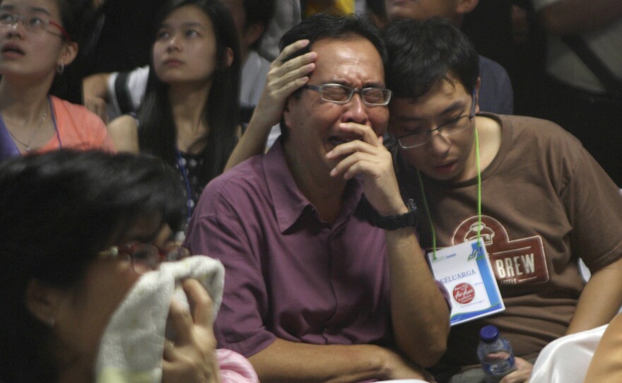 Relatives of passengers of the missing AirAsia Flight 8501 react upon seeing the news on television about the findings of bodies on the waters near the site where the jetliner disappeared in Surabaya, East Java, Indonesia, on Tuesday.