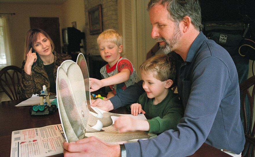 Jennifer May watches her sons Wyndham and Carson introduce children's storybooks to Mike May, after surgeries to correct blindness in one of Mike’s eyes in 2000.