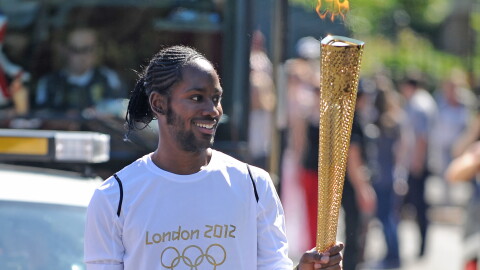 FILE — Torchbearer Jason Arday carries the Olympic Flame on the Torch Relay leg between Sutton and Merton, in London, July 23, 2012.
