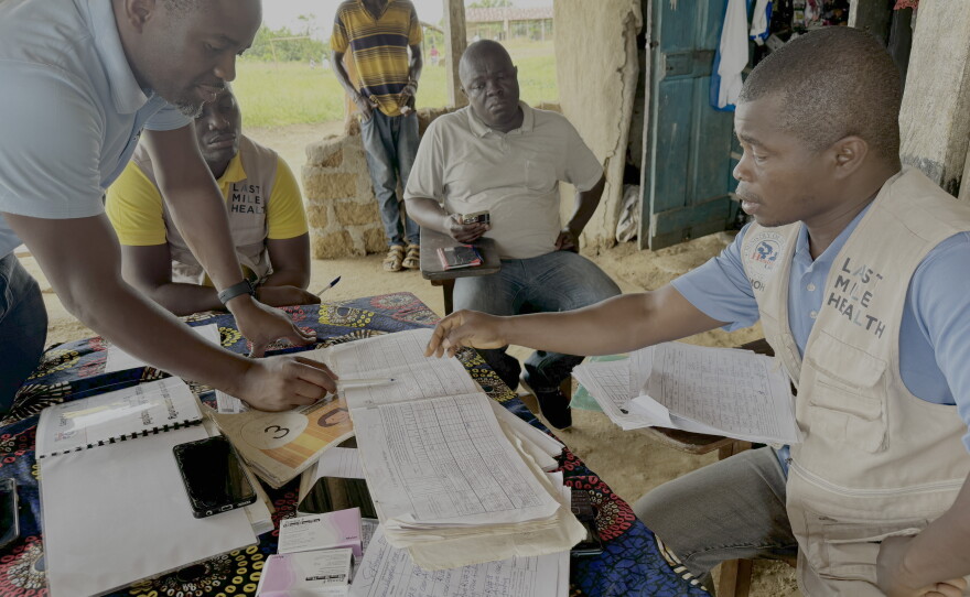 Genesis Whegelee (right, in vest) has been a community health worker for Last Mile Health in Rivercess County, Liberia, since 2018. He visits households to keep an eye on sick children, pregnant moms and anyone with a problem that needs diagnosing.