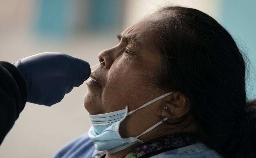 Leticia Lopez gets her sample collected for a COVID-19 test at a pop-up testing and vaccination site outside a swap meet in Los Angeles, Wednesday, Dec. 15, 2021.