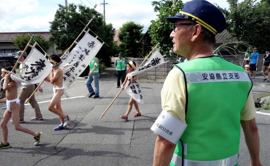 Locals volunteer as crossing guards for the parade through town in Nagano Prefecture. The boys walk about a mile in sweltering July heat.