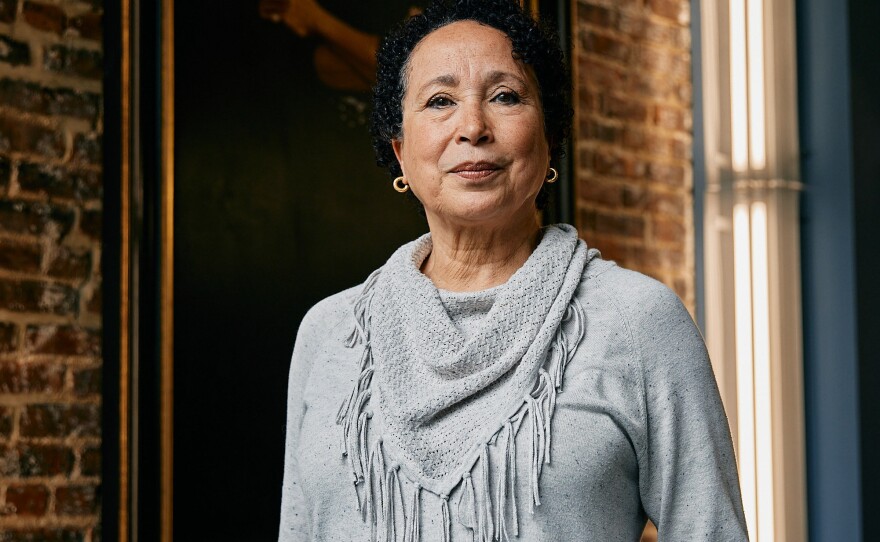 Virginia Johnson, the outgoing artistic director of Dance Theatre of Harlem, poses in front of a painted portrait of founder Arthur Mitchell on Thursday, June 22, 2023.