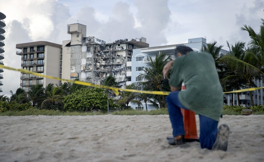 A man prays near where search and rescue operations continue at the site of the Champlain Towers South condo building on Friday. The man, overcome with emotion, said he had lost a relative in the collapse.