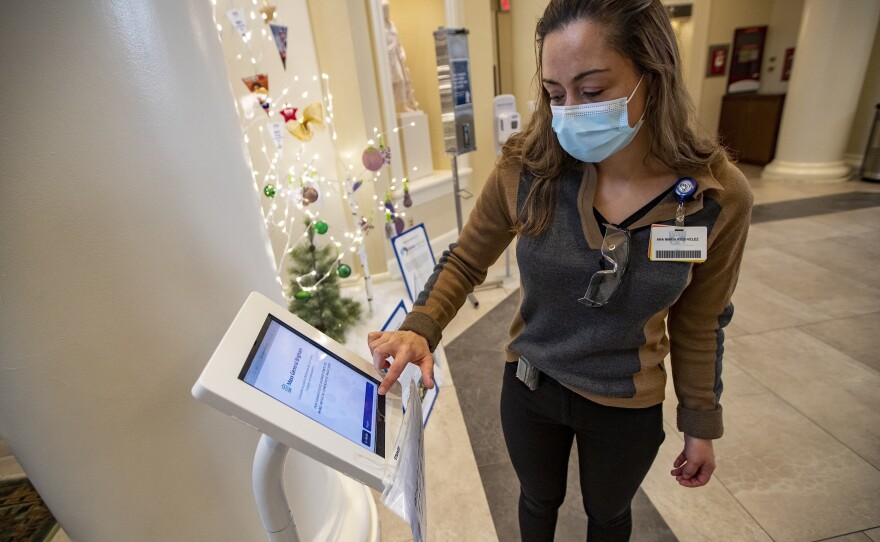 Interpreter Ana Maria Rios-Velez demonstrates the screening app at the front entrance of Brigham and Womens Hospital in Boston. It has a multilingual function to better communicate with non-English speaking patients and staff.