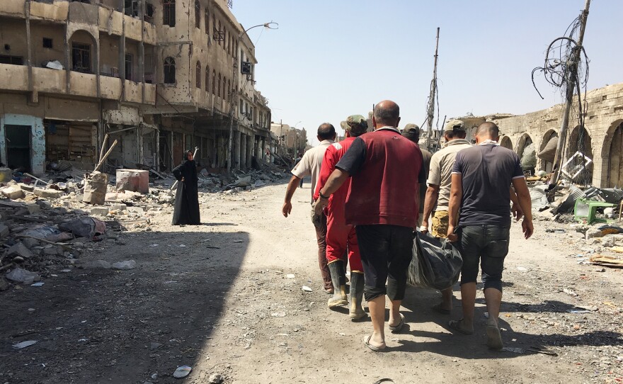 Civil defense workers carrying the body of a civilian retrieved from the rubble of a house destroyed in airstrike. They've collected almost 1,500 bodies so far in west Mosul – many of them women and children – and are still finding casualties.