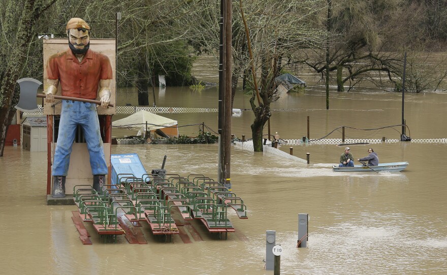 Two men use a rowboat to make their way through a flooded RV park near Forestville, Calif., on Monday.