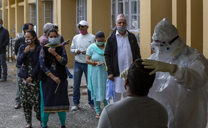 A health officer in protective suit collects a swab sample to be tested for coronavirus on Thursday in Dharmsala, India. India's confirmed  coronavirus caseload surpassed 8 million on Thursday.