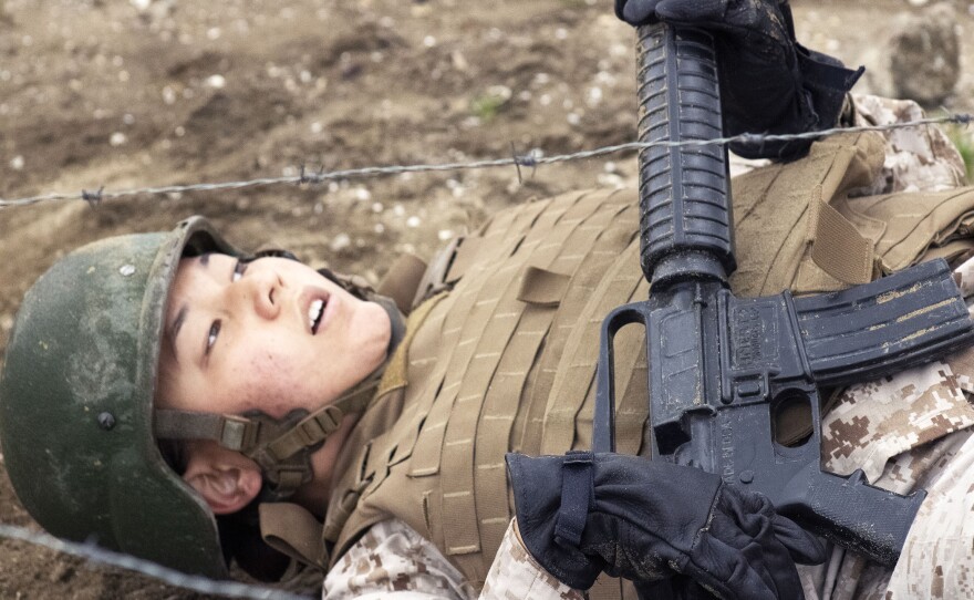 A Marine recruit from Lima Company crawls under barbed wire during the Bayonet Assault Course at Marine Corps Recruit Depot, San Diego, March 23, 2021.