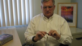 Wayne Savell examines his uncle's dog tag that he wears to remind himself of his family's proud military background